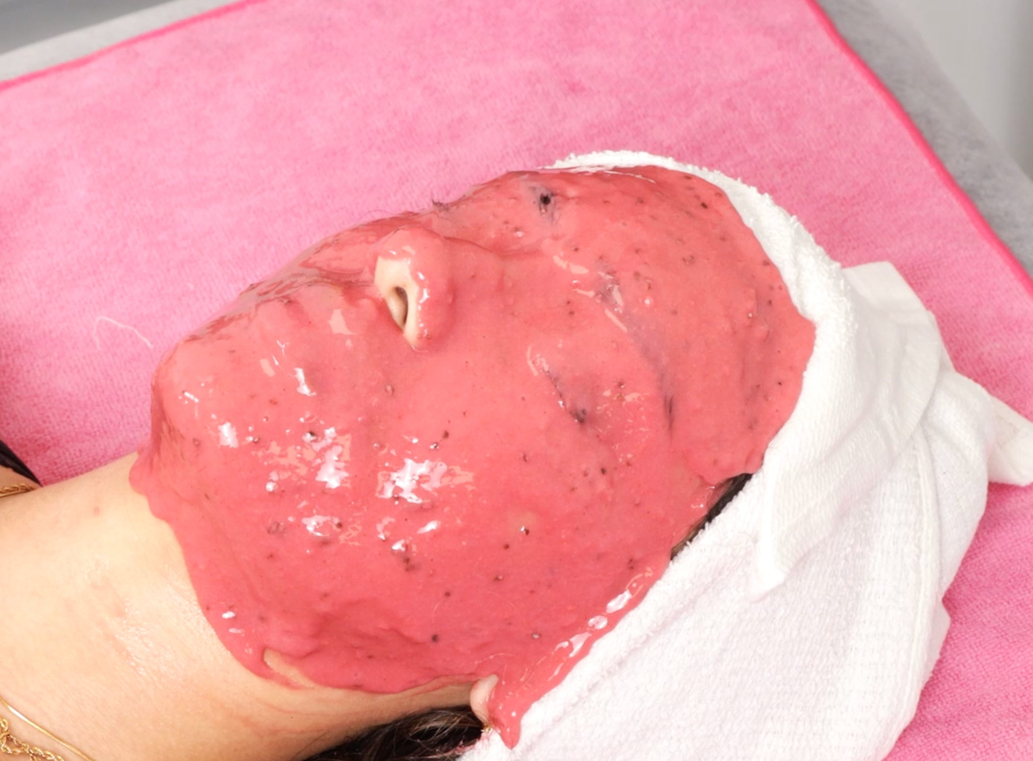 A jelly mask being applied over a client's face in a treatment room