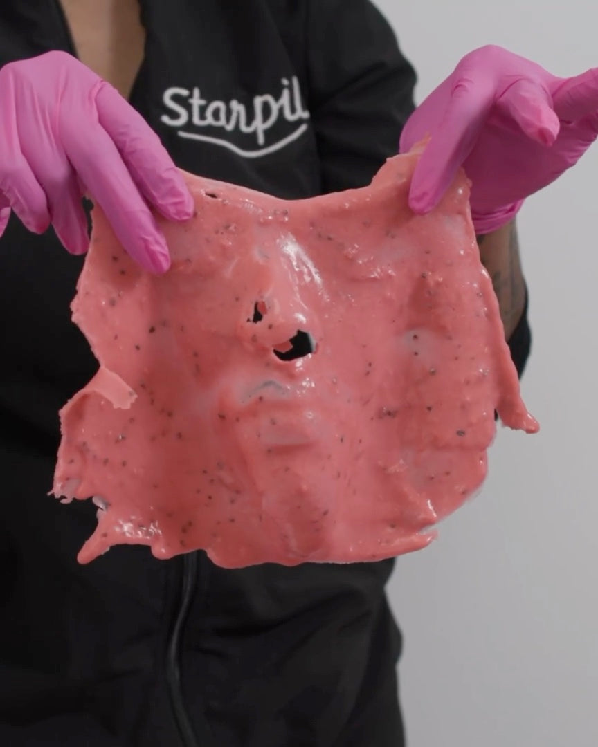 A set jelly mask peeled off in one whole piece, held up by the esthetician